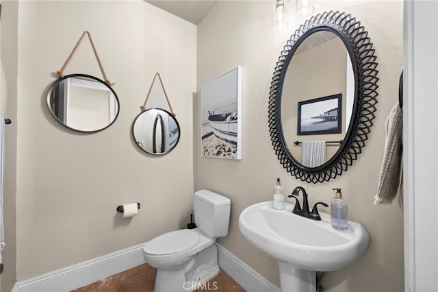 bathroom with baseboards, a sink, and toilet