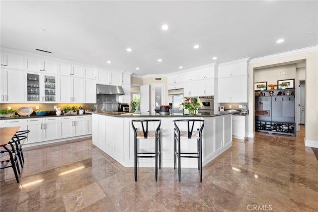 kitchen with marble finish floor, dark countertops, appliances with stainless steel finishes, white cabinets, and under cabinet range hood