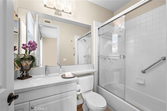 bathroom with toilet, shower / bath combination with glass door, vanity, and visible vents