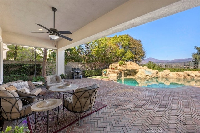 view of patio with a fenced in pool, a ceiling fan, area for grilling, fence, and a mountain view