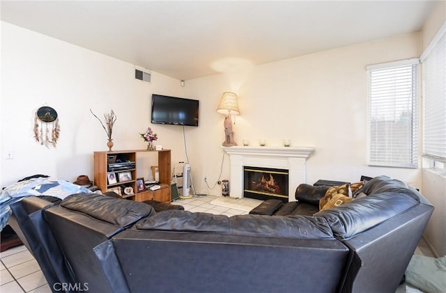 living room featuring a glass covered fireplace, visible vents, and light tile patterned floors