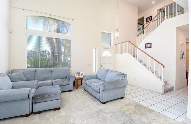 living room featuring stairs, plenty of natural light, and a towering ceiling