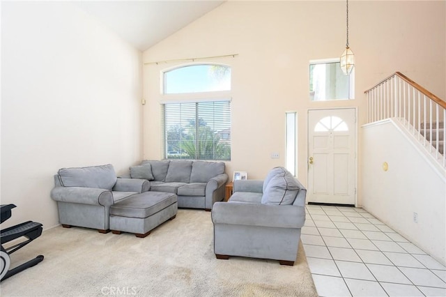 living room with high vaulted ceiling, light colored carpet, stairway, and light tile patterned floors