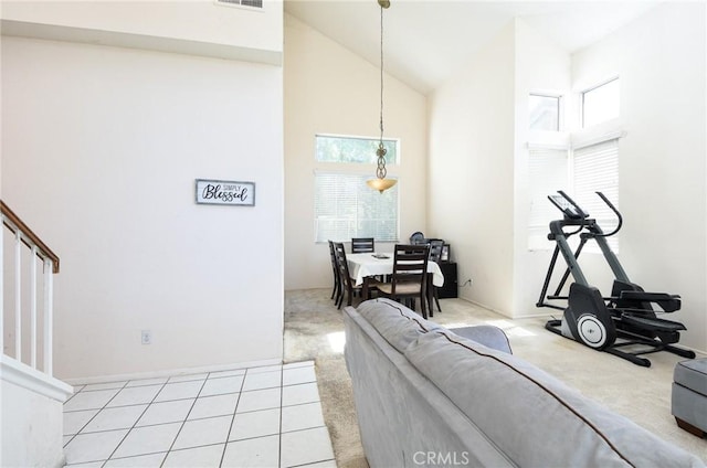 living area with light carpet, a healthy amount of sunlight, and high vaulted ceiling