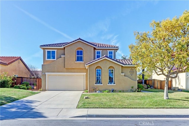 mediterranean / spanish home featuring stucco siding, fence, driveway, a tiled roof, and a front lawn