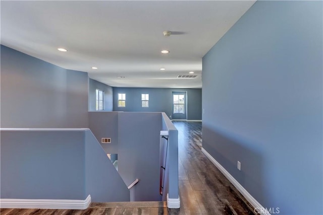 hallway featuring visible vents, baseboards, wood finished floors, an upstairs landing, and recessed lighting