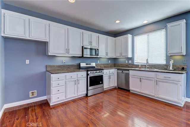 kitchen featuring white cabinets, dark wood-style floors, stainless steel appliances, a sink, and recessed lighting