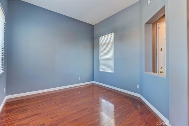 empty room featuring dark wood-type flooring and baseboards