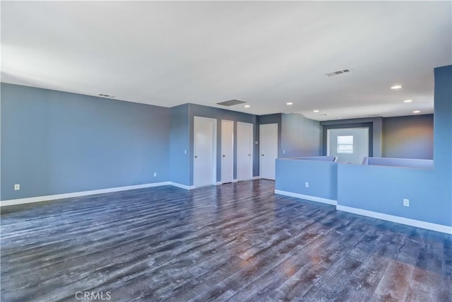 empty room featuring wood finished floors, visible vents, and baseboards