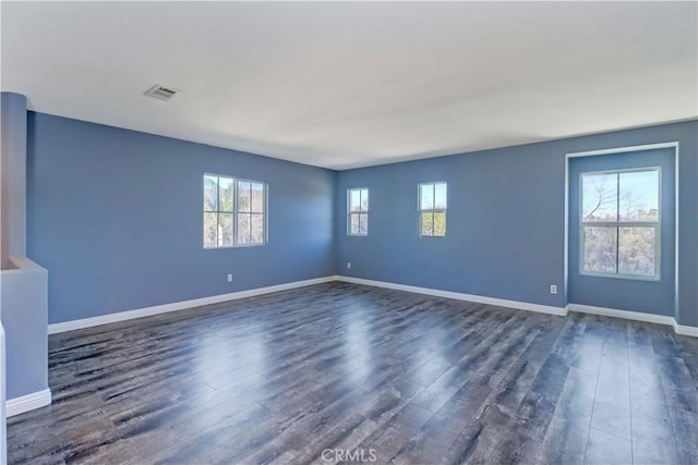 unfurnished living room with baseboards, visible vents, and dark wood finished floors