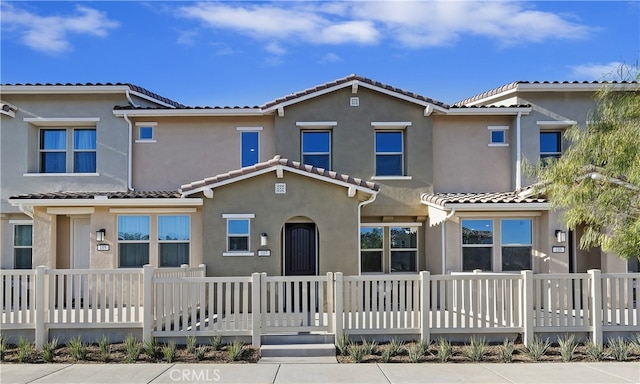 townhome / multi-family property featuring a tiled roof and stucco siding