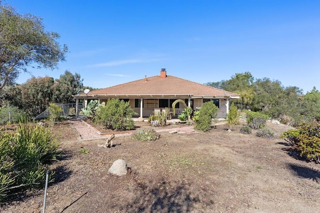 rear view of house featuring a chimney and a tile roof