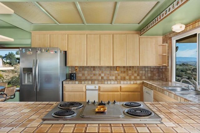 kitchen with stainless steel refrigerator with ice dispenser, tile countertops, electric cooktop, light brown cabinetry, and a sink