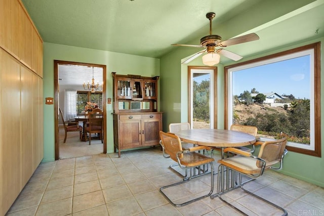 dining area with light tile patterned floors and ceiling fan with notable chandelier