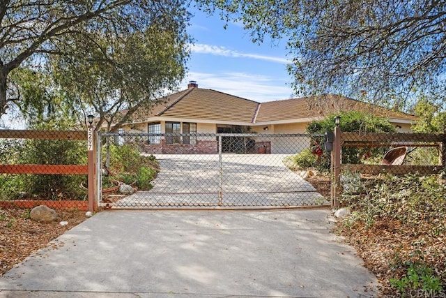 ranch-style home featuring driveway, a fenced front yard, a gate, and a tile roof