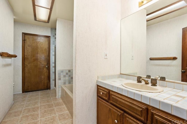 bathroom featuring tile patterned flooring, vanity, and a tub