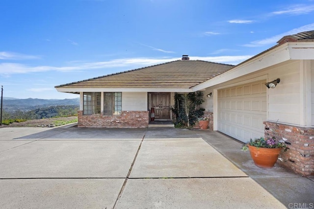 exterior space with brick siding, a mountain view, driveway, and an attached garage