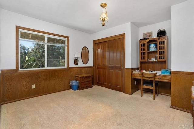 office featuring wooden walls, wainscoting, and light carpet