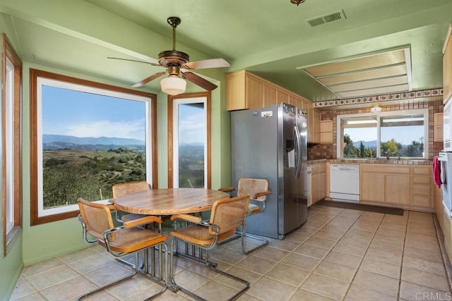 kitchen featuring stainless steel refrigerator with ice dispenser, visible vents, light brown cabinets, a mountain view, and dishwasher