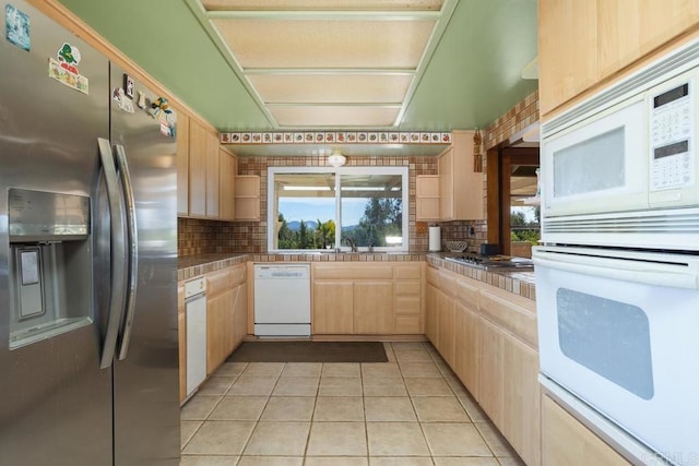 kitchen with stainless steel appliances, light tile patterned flooring, light brown cabinets, and decorative backsplash