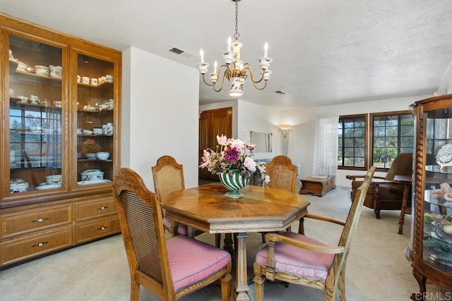 dining space with light carpet, a textured ceiling, visible vents, and a notable chandelier