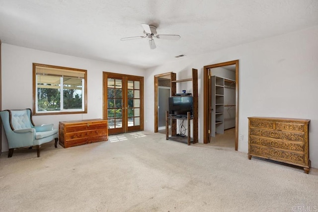 living area featuring french doors, light carpet, ceiling fan, and visible vents