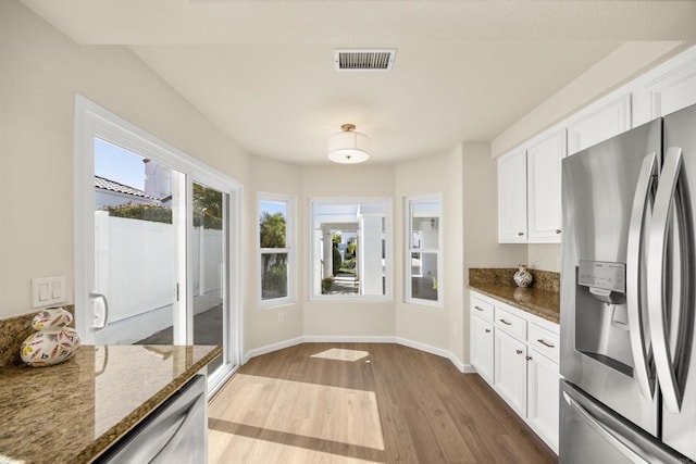 kitchen featuring white cabinetry, visible vents, dark stone counters, and stainless steel appliances