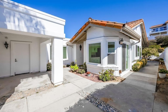 exterior space featuring a tile roof, fence, a patio, and stucco siding