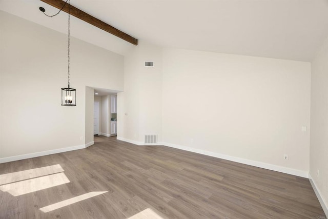 unfurnished living room featuring visible vents, beamed ceiling, baseboards, and wood finished floors