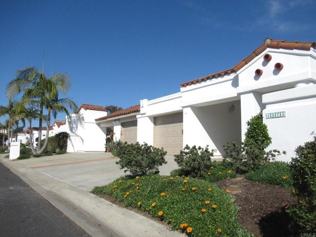 view of front of house with a garage, a tiled roof, and stucco siding