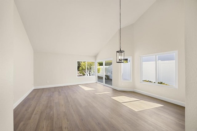 unfurnished living room featuring high vaulted ceiling, baseboards, and wood finished floors