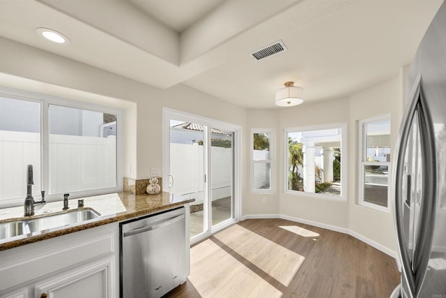 kitchen with visible vents, appliances with stainless steel finishes, dark stone countertops, white cabinetry, and a sink