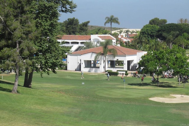 view of property's community with view of golf course and a lawn