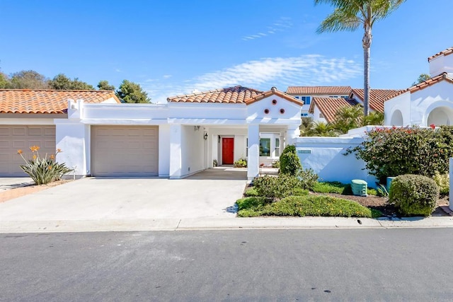 mediterranean / spanish-style house with concrete driveway, a tile roof, an attached garage, and stucco siding