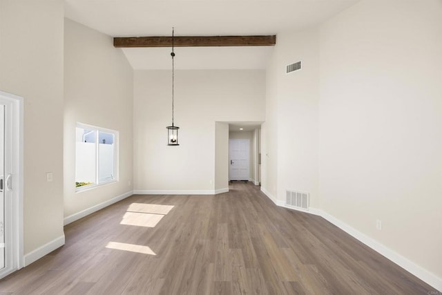 unfurnished dining area featuring baseboards, visible vents, and beamed ceiling