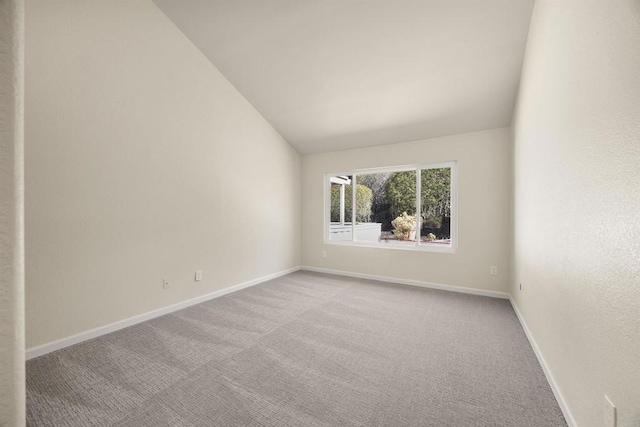 unfurnished room featuring vaulted ceiling, light colored carpet, and baseboards