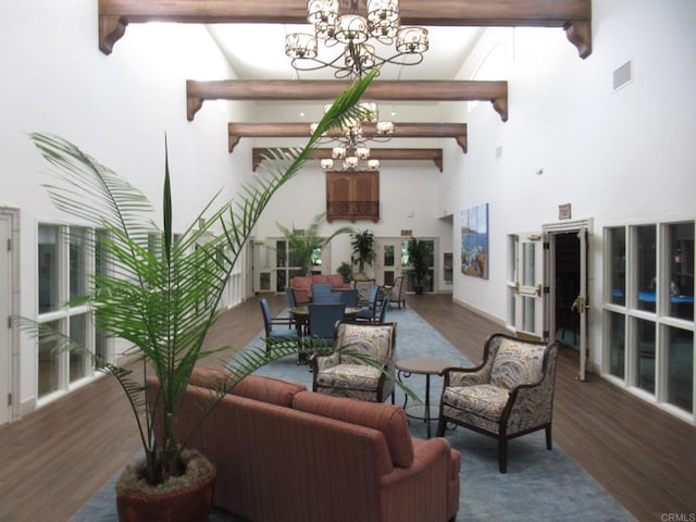 interior space with visible vents, wood finished floors, a notable chandelier, a high ceiling, and beam ceiling