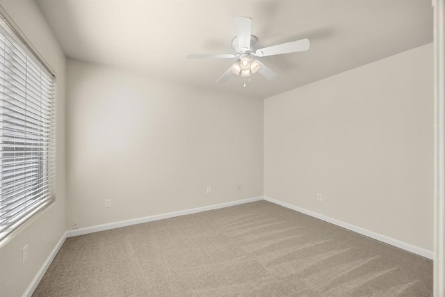 carpeted spare room featuring ceiling fan, plenty of natural light, and baseboards