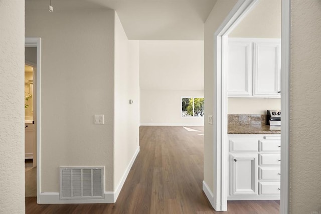 hallway with visible vents, baseboards, and wood finished floors