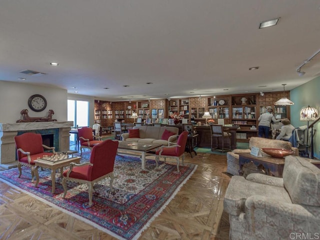 living area featuring rail lighting, built in shelves, visible vents, and a high end fireplace