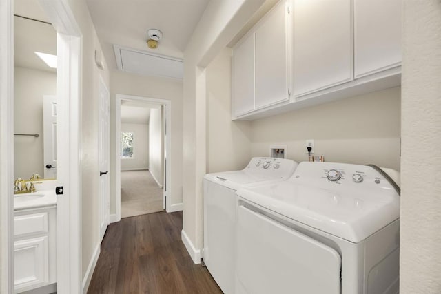 washroom with washing machine and dryer, dark wood-style flooring, a sink, baseboards, and cabinet space