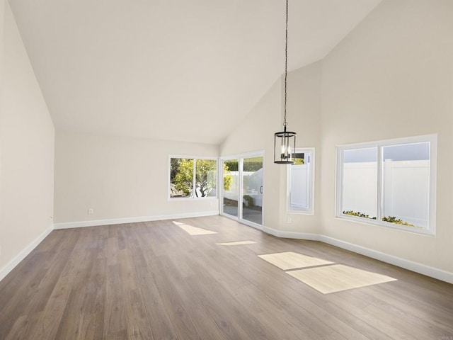 unfurnished living room featuring wood finished floors, baseboards, and high vaulted ceiling