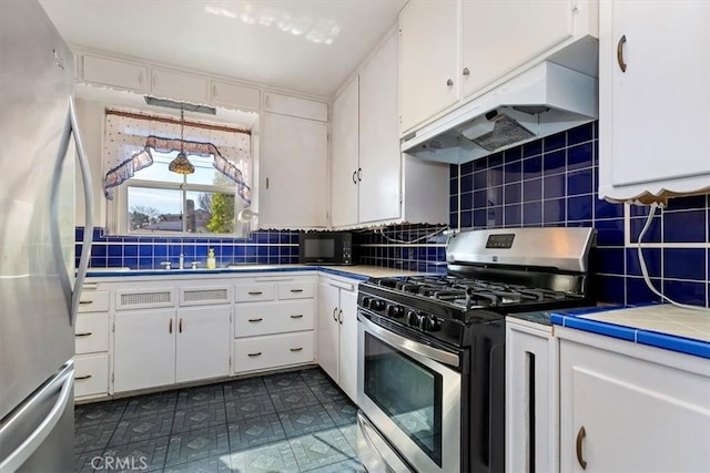 kitchen featuring appliances with stainless steel finishes, white cabinetry, under cabinet range hood, and decorative backsplash