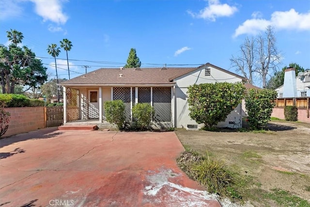 view of front of home with a shingled roof, fence, and stucco siding