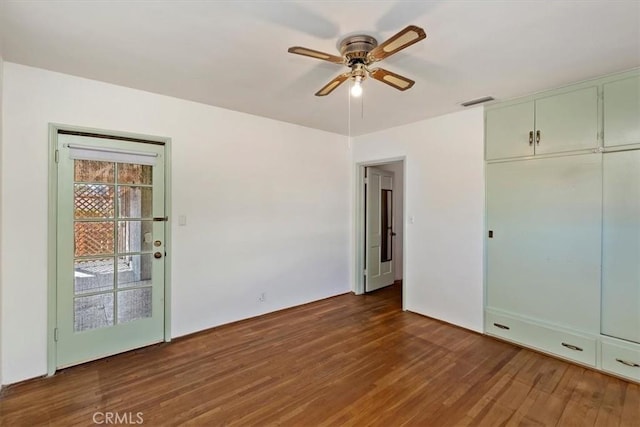 unfurnished bedroom with a ceiling fan, dark wood-style flooring, and visible vents