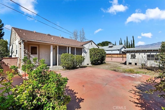 rear view of house with a patio area, fence, and stucco siding