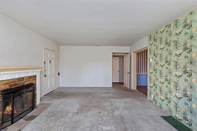 unfurnished living room featuring a fireplace with flush hearth and carpet floors