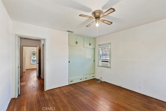 unfurnished bedroom with a closet, wood finished floors, and visible vents