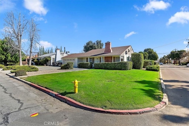 ranch-style home with driveway, a chimney, an attached garage, and a front yard