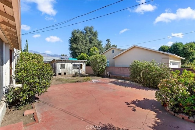 view of patio / terrace with a garage, an outbuilding, a fenced backyard, and a mountain view